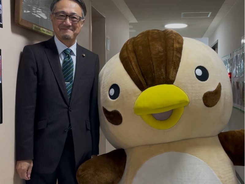 マスコットキャラクターと並ぶ吉田賢一