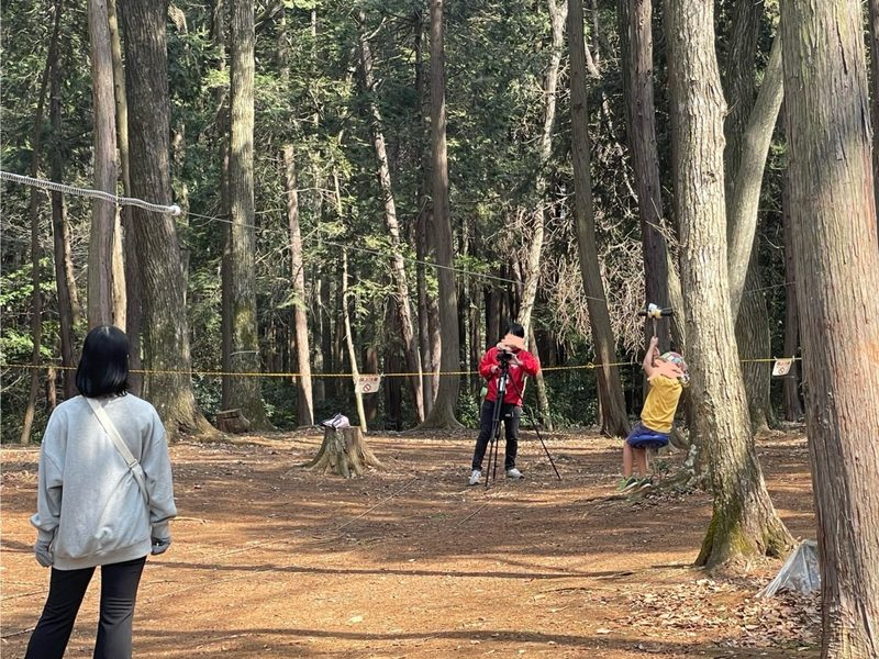 林の中の遊び場で、ロープにつかまって遊ぶ子ども